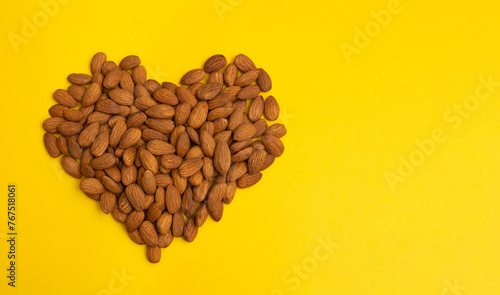 Close-up peeled almonds nuts heart yellow background top view using for your advertising (ID: 767518061)