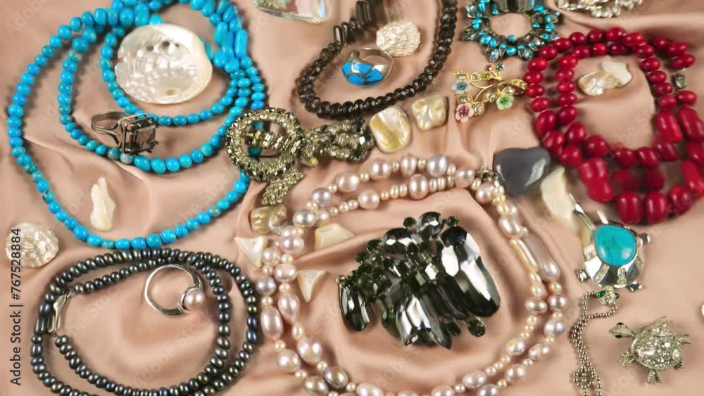 Jewelry made of precious stones and pearls on a beige silk background underwater. Ripples on the surface of clear water. Jewelry made of precious stones and pearls on a beige silk background underwater. Ripples on the surface of clear water.