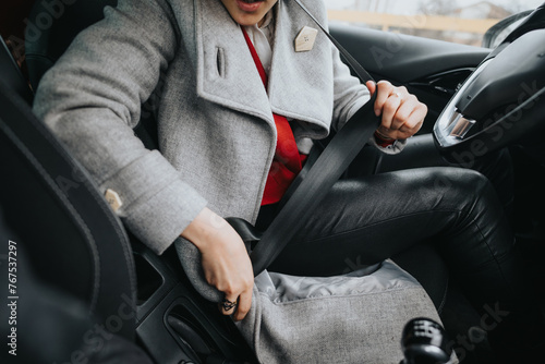 A businesswoman secures her seat belt in a vehicle, showcasing responsibility and safety.