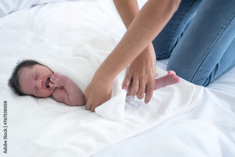 Mother is changing the diaper of her crying baby in bed at home Mother is changing the diaper of her crying baby in bed at home