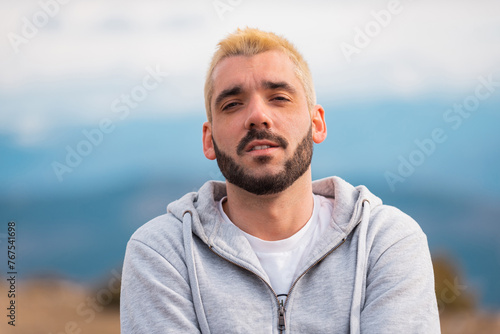 Portrait of a young bearded man outside looking at camera.