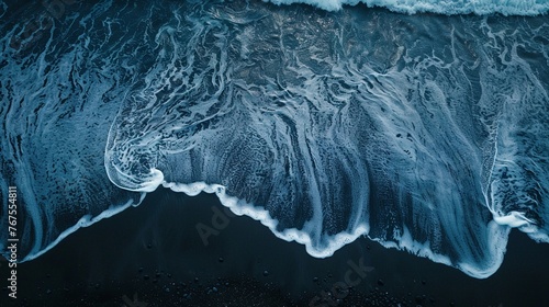A Foamy blue waves meet the dark sands of a beach