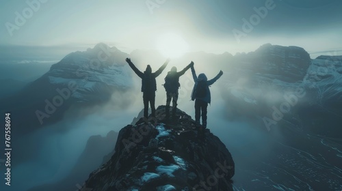 Together overcoming obstacles with three people holding hands up in the air on mountain top , celebrating success and achievements photo