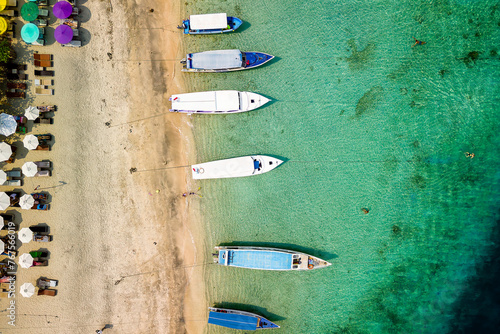 Birds eye view of colorful sun umbrellas and boats on a small, warm tropical beach © whitcomberd