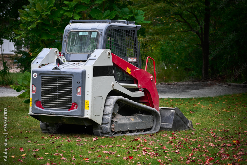 skid steer sitting in a yard on grass after building a gravel driveway.