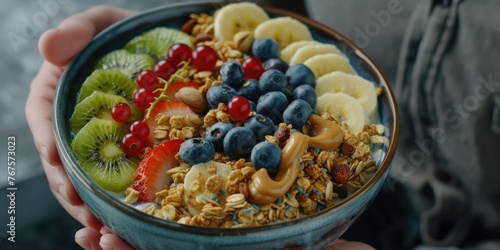 Bowl of fruit and granola is being held by person