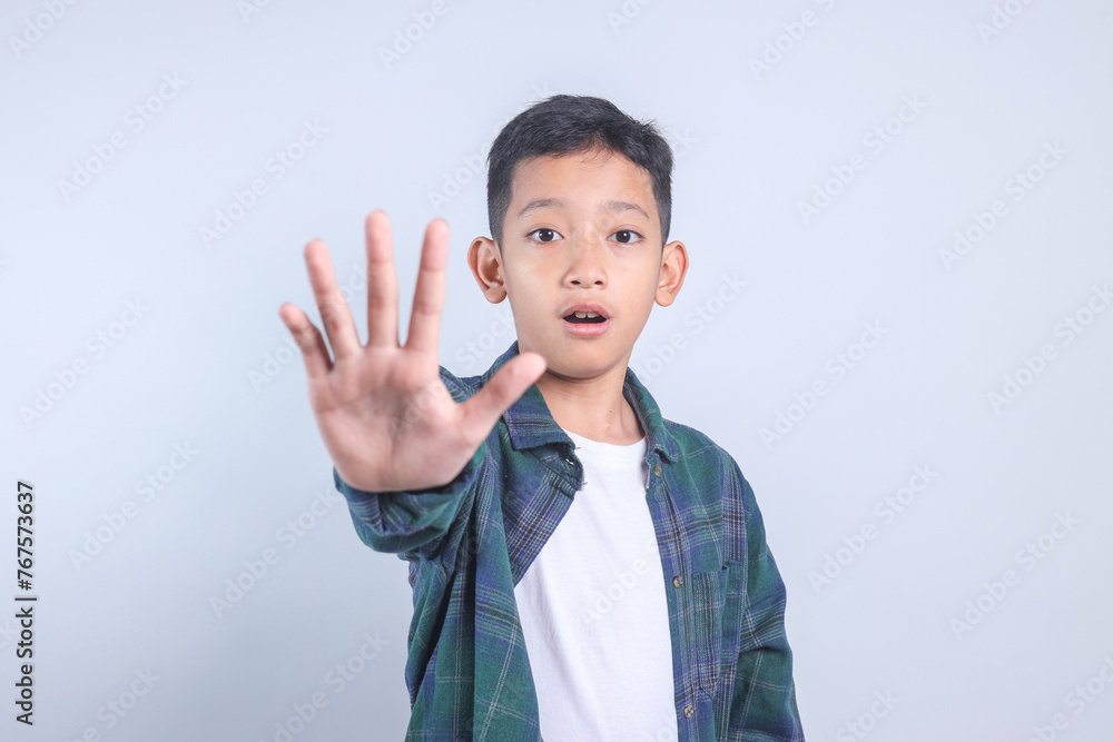 Little boy doing rejection expression, showing stop or no hand gesture on grey background Little boy doing rejection expression, showing stop or no hand gesture on grey background