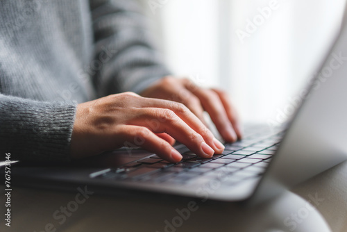 Closeup image of a woman typing on laptop computer at home