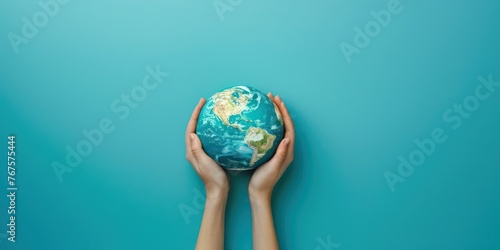 Two hands cradle a miniature Earth globe on vivid blue background top view copy space 