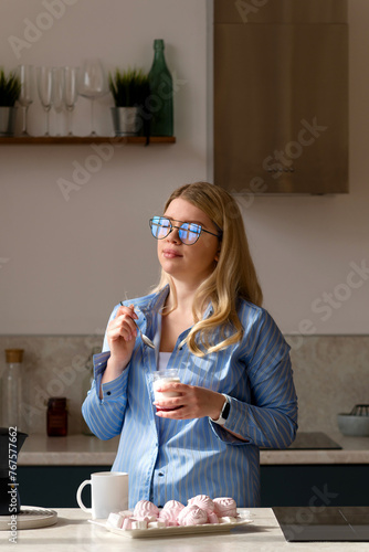 Woman tasting yogurt in sunlit kitchen