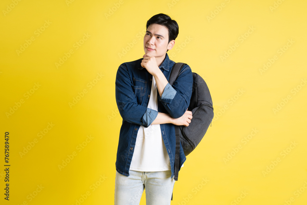 Portrait of Asian male student posing on yellow background Portrait of Asian male student posing on yellow background