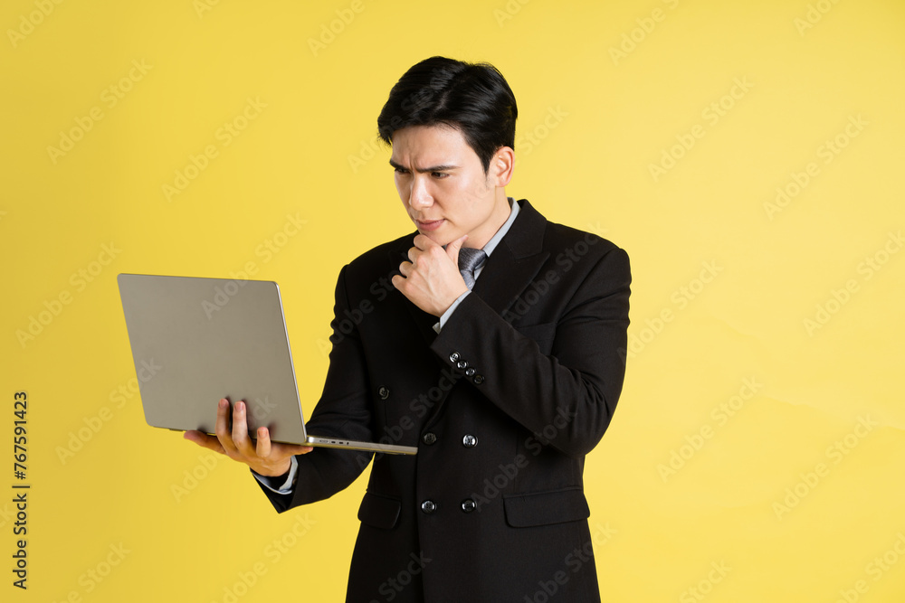 Portrait of Asian male businessman. wearing a suit and posing on a yellow background Portrait of Asian male businessman. wearing a suit and posing on a yellow background