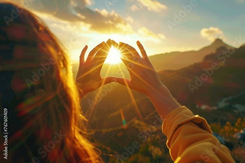 A woman is holding her hands together in a heart shape to capture the sun. Concept of warmth, love, and positivity