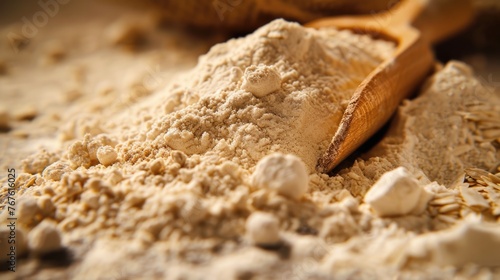 Close-up of wheat flour with grains and a wooden scoop.