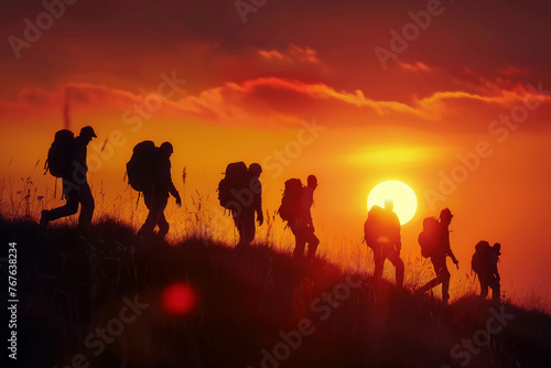 A group of people walks through the mountains at sunset
