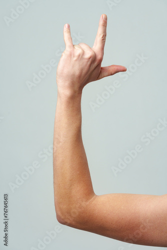 Male hand gesturing rock and roll on gray background