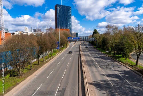 Mancunian Way Manchester 6 lanes road with cars driving over and white clouds on the sky.  photo