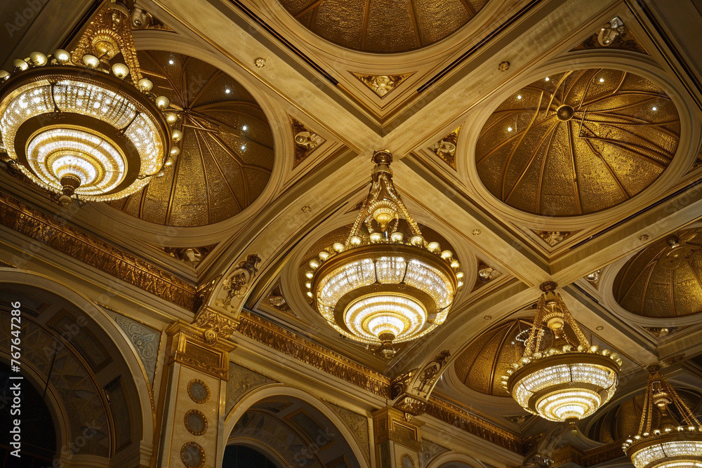 Fototapeta premium An opulent ceiling with a series of gold-leafed domes, each featuring a central, ornate chandelier, evoking the grandeur of a bygone era.