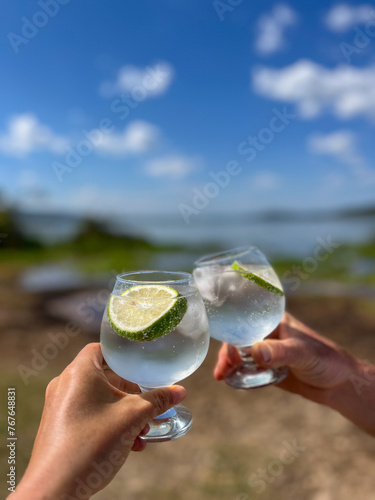 close up of two hands of two persons toasting and  holding a glass of gin and tonic
