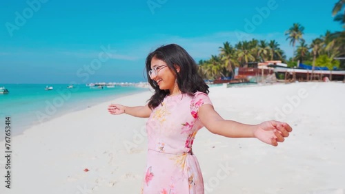 Teenager Indian girl enjoying sunny summer day with spreading arms and breathing fresh air at beach in Lakshadweep, India. Travel and holidays concept. photo