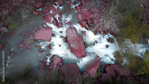 Vertical drone video shot of a river in a red stone canyon with a road next to it. Drone video 4k