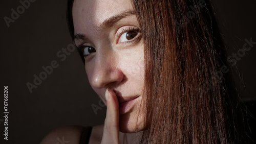 Woman puts a finger to her lips, a close-up face. Concept - yin and yang, light and darkness, non-verbal communication, silence, conspiracy photo