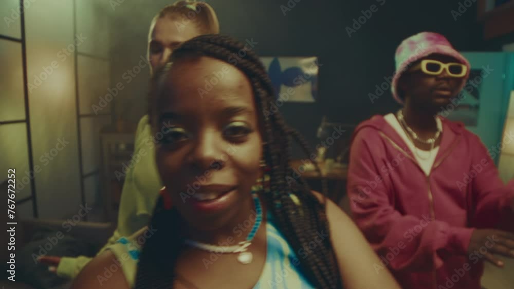 Medium slowmo of ethnically diverse young eccentric dancing trio in stylish vibrant outfits looking at camera and dancing in neon light smoke filled room Medium slowmo of ethnically diverse young eccentric dancing trio in stylish vibrant outfits looking at camera and dancing in neon light smoke filled room