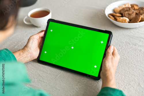 tablet with green screen chromakey display in elderly woman hand