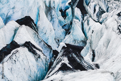 Ice crevasse on an Icelandic glacier with black volcanic ash on top photo