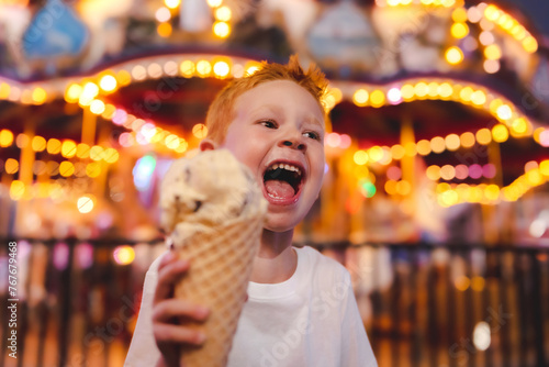 Young smiling boy holding an ice cream cone with ferris wheel photo