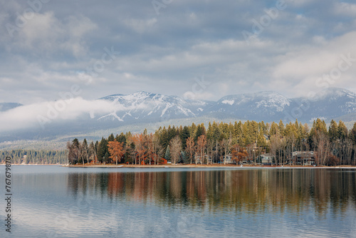 Whitefish lake in winter with trees and houses reflected in water photo