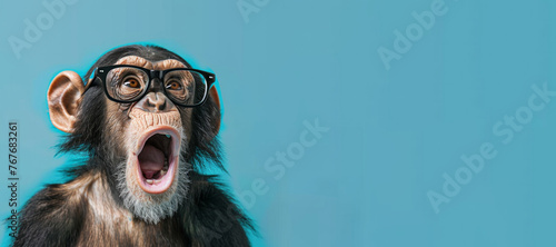 A baby monkey wearing glasses and an open mouth. Concept of curiosity and playfulness. Surprised chimpanzee wear glasses on bright blue background