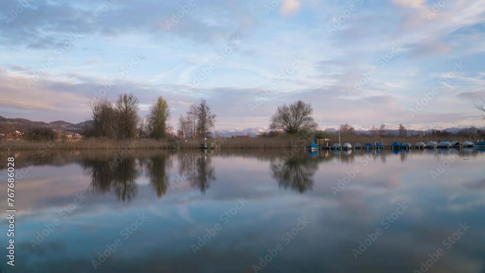 Beautiful sunset on a lake with mountains in the background and boats on the lake. The sky turns pink. Beautiful sunset on a lake with mountains in the background and boats on the lake. The sky turns pink.