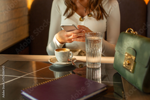 Woman hand holding smartphone, taking photo of a cup of coffee
