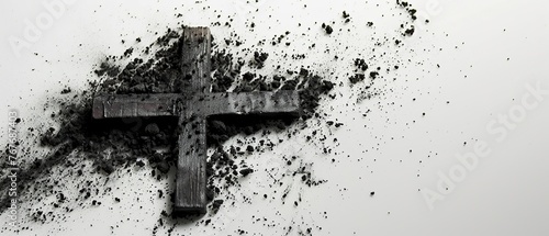A cross is surrounded by a cloud of ash. The ash is black and white, and it covers the entire cross. Concept of destruction and loss, as the cross is no longer recognizable photo
