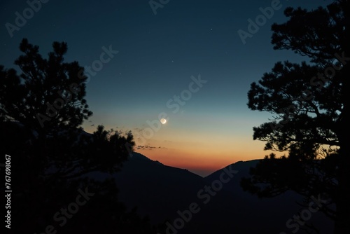 Beautiful mountain landscape at sunset. Silhouettes of mountains and crescent moon