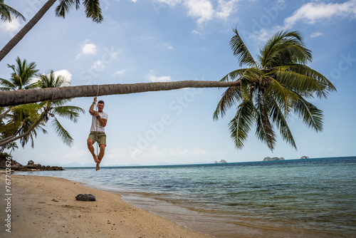 Mężczyzna na rajskiej plaży wisi na palmie © DawidFastMan