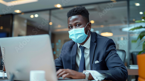 black businessman wearing surgical mask and working with laptop in the office