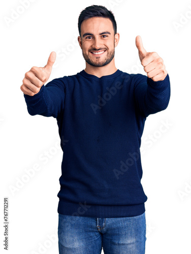 Young handsome man wearing casual clothes approving doing positive gesture with hand, thumbs up smiling and happy for success. winner gesture.