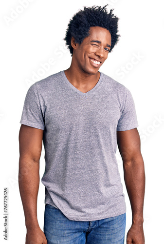 Handsome african american man with afro hair wearing casual clothes winking looking at the camera with sexy expression, cheerful and happy face.