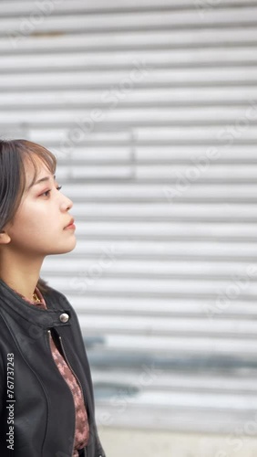 Slow motion vertical video of a young Japanese woman in her early 20s from Okinawa Prefecture in her 20s walking on Kokusai Street in Naha City, Okinawa Prefecture 沖縄県那覇市の国際通りを歩く20代の沖縄県出身の２０代前半の若い日本人女 photo