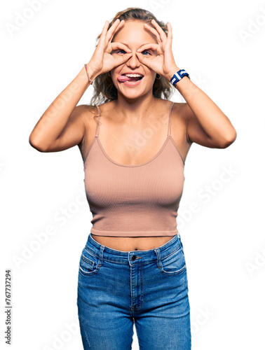 Beautiful caucasian woman wearing casual clothes doing ok gesture like binoculars sticking tongue out, eyes looking through fingers. crazy expression.
