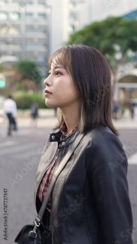 Slow motion vertical video of a young Japanese woman in her early 20s from Okinawa Prefecture in her 20s walking on Kokusai Street in Naha City, Okinawa Prefecture 沖縄県那覇市の国際通りを歩く20代の沖縄県出身の２０代前半の若い日本人女 photo