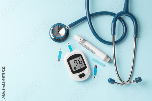 Blood glucose meter, lancet and stethoscope on blue background, diabetes concept