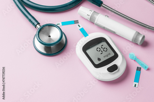 Blood glucose meter, lancet and stethoscope on pink background, diabetes concept photo