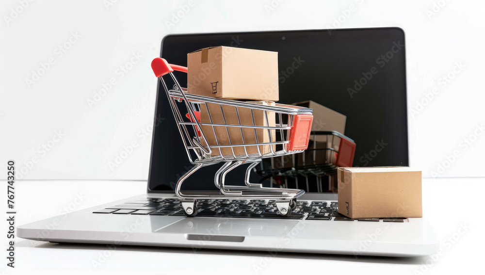 A miniature shopping cart with boxes inside is placed on top of an open laptop computer, symbolizing the concept of online retail and ecommerce
