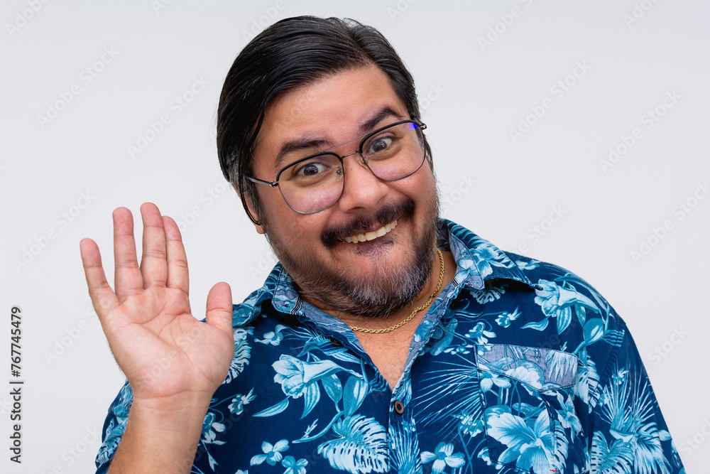 A cheerful, nerdy man wearing glasses and a Hawaiian shirt appears slightly embarrassed as he gives an awkward wave.