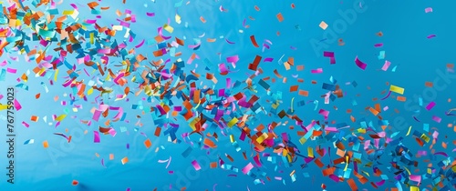 Colorful confetti falling on a blue background with copy space for a celebration or party design. Happy new year, anniversary or birthday concept. © Sabina Gahramanova