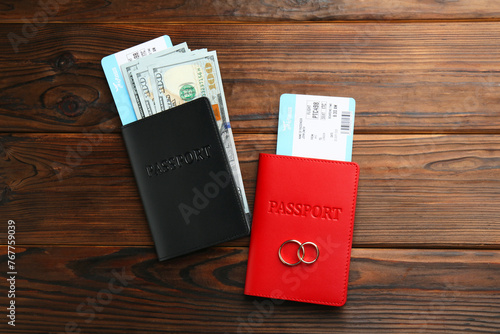 Honeymoon concept. Two golden rings, passports, money and tickets on wooden table, top view