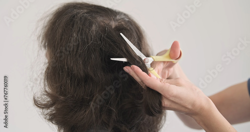 Cut off lock of hair. Woman's hand cuts off lock of hair on man's head with scissors. Back view, unrecognizable. Stiff long hair.